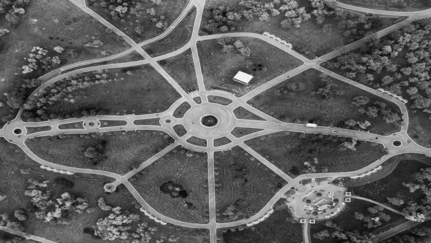 Aerial view of a lush green park with winding pathways and scattered trees.