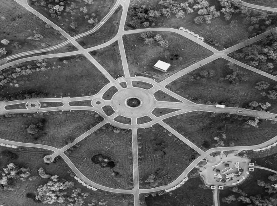 Aerial view of a lush green park with winding pathways and scattered trees.